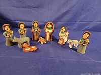 Front view of all 10 hand-painted Jemez Pueblo nativity figures arranged on blue backdrop
