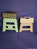 Front view of green and beige folding step stools standing upright