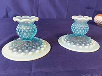 Pair blue opalescent hobnail candlesticks on purple background