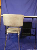 Rear view of gray upholstered chair and partial desk frame