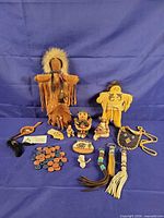 Overview of entire lot including dolls, storyteller figurines, dreamcatcher, keychains, canoe, beads, fetish bag and wooden tiles