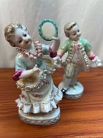 Both porcelain child figurines on wood surface