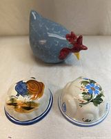 Blue ceramic hen and two domed plaques on surface
