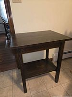 Full view of dark walnut accent table showing top, legs and lower shelf