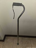 Full view of aluminum cane showing handle, wrist strap, adjustment holes and rubber tip