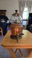 Front view of copper pot with brass spigot and glass globe