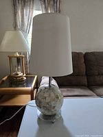 Lamp unlit showing full structure: mosaic shell base, chrome stem, glass foot, white cylindrical shade, power cord