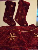Tree skirt and two stockings displayed together, showing color and matching embroidery