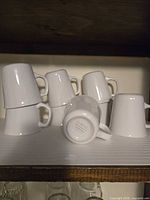 Group of white Corelle mugs, some upside down showing base mark
