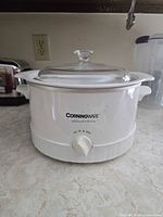 Front view of CorningWare Electrics slow cooker showing brand logo, control knob, glass lid