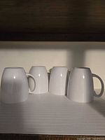Four white mugs upside down, showing shape and finish