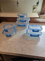 All seven glass containers stacked showing both round and rectangular shapes with lids