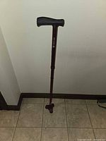 Full view of adjustable maroon aluminum cane with tripod base and black handle