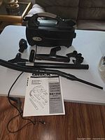 Overall view of Oreck BB1200 canister vacuum with attachments and manual on table