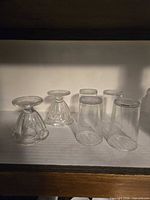 Two clear glass pedestal sundae dishes and four cylindrical juice glasses