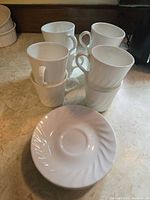 Stacked white teacups and saucers showing overall quantity and style