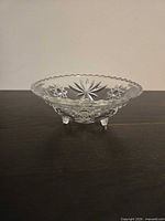 Side view showing 3 feet and scalloped rim of clear glass bowl