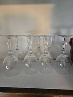 Eight inverted clear wine glasses showing stems and bowls