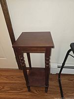 front view of small mahogany stained wooden accent table with lower shelf