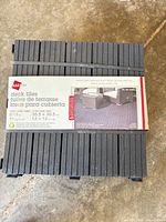 Front view of packaged stack of EASYtile interlocking deck tiles showing label and color
