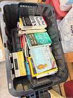 Plastic tote containing stack of assorted books