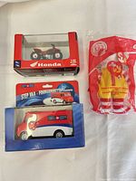 All three packaged items laid out: ATV, step van, plush