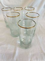 Six clear highball glasses standing upright on white cloth