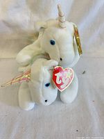 Two Ty Mystic unicorn plush toys stacked showing front view, horns, eyes, swing tags