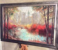 Frontal view of framed acrylic cityscape painting on easel