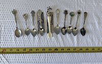 All ten spoons lined up with tape measure for scale