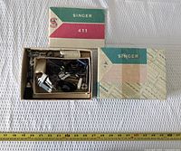 Overall view of open Singer 411 box with contents and tape measure for scale
