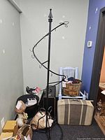 Full view of tall black spiral wrought iron hat rack with hooks and scroll base