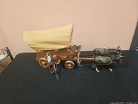 Side view of covered wagon lamp with mules and driver
