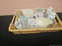 Overview of assorted creamers, pitchers and shakers in wicker basket