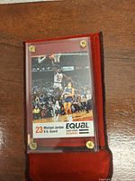 Front of promotional card in acrylic case with red velvet pouch base visible