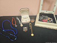 Overview of all items laid out: necklaces, earrings, pendant watch, heart pendant, two jewelry boxes