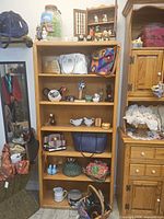 Full bookshelf showing variety of ceramics, handbags and decor