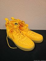 Side and front view of both yellow high-top sneakers