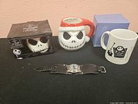 Overall lot showing three mugs, boxed mug, watch