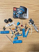 Overview of loose Technic parts, wheels, minifigure and manual on table