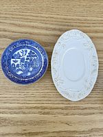 Blue Willow saucer and white grapevine platter side by side