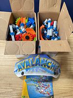 Two boxes of assorted Marble Mania Avalanche track pieces with logo header and instruction manual in front