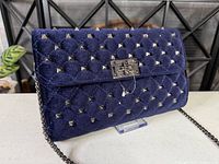 Front view of navy velvet quilted bag with studs and turn-lock