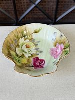 Top view of shell-shaped dish with rose motif and gold rim
