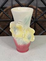 Front view of ceramic vase showing cream to pink gradient and raised yellow flowers