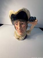 front view of ceramic character jug, showing face, hat and handle details