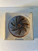 Top of box displaying image of spiral-pattern plate and Romania marking