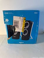 Front of damaged retail box showing Logitech Z200 speaker image and torn section