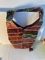 Front view of multicolor patchwork shoulder bag showing embellishments and tassel