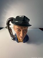 Front view of glazed ceramic male character jug with pistol-shaped handle